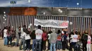 Keluarga yang dipisahkan saling bertemu melalui dinding perbatasan antara Meksiko dan Amerika Serikat di Ciudad Juarez, 10 Desember 2017. Keharuan terjadi ketika mereka hanya bisa menggenggam tangan keluarga dari balik dinding. (Herika MARTINEZ/AFP)