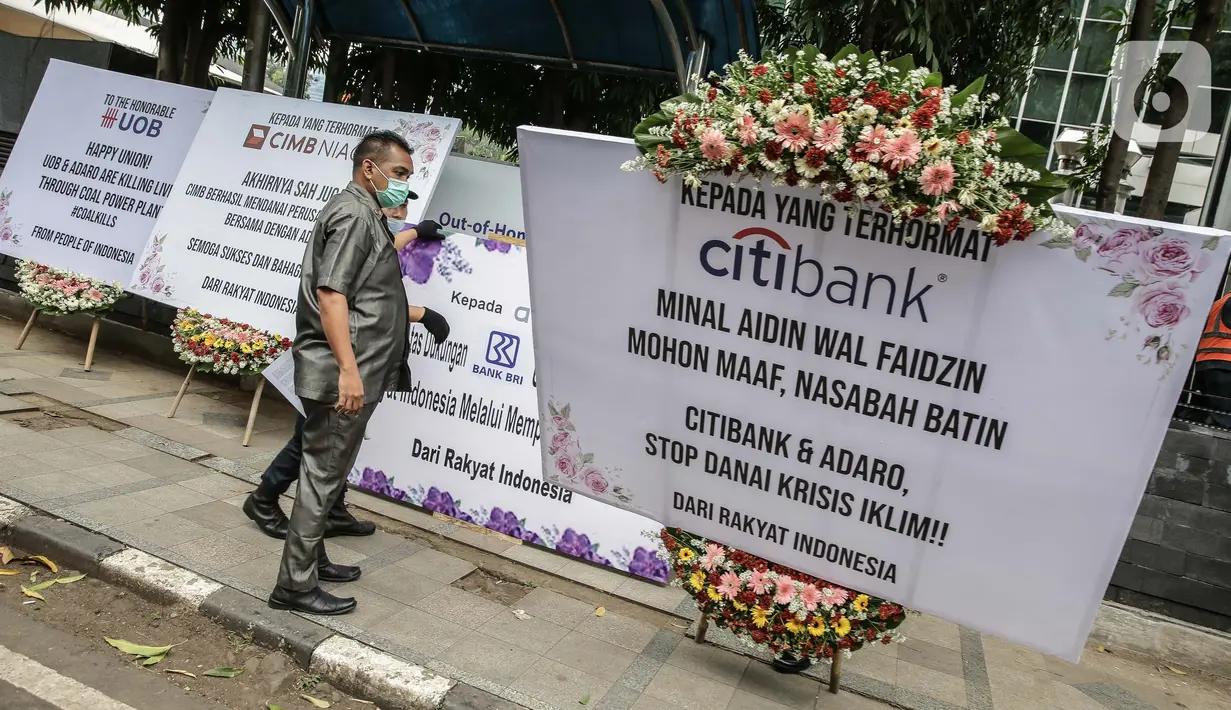 Security menurunkan karangan bunga di depan Kantor Adaro, Jakarta, Senin (3/5/2021). Gerakan Extinction Rebellion Indonesia mengirim karangan bunga yang ditujukan kepada sindikasi perbankan pemberi pinjaman dan Adaro. (Liputan6.com/Faizal Fanani)