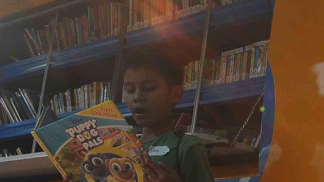 Seorang tampak sedang membaca ragam buku cerita dongeng di depan mobil Perpustakaan Keliling di Taman Menteng, Jakarta, Senin (14/8/2023).