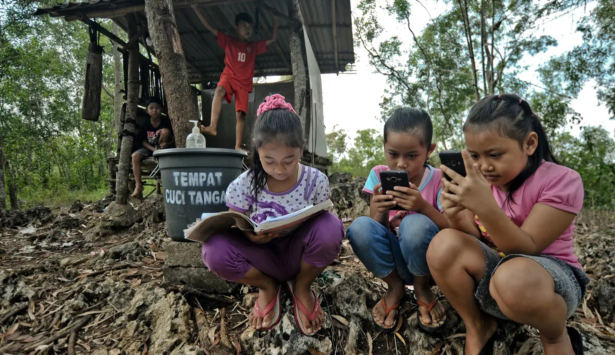 Siswa sekolah dasar mengikuti pembelajaran secara online menggunakan smartphone mereka di bukit Temulawak, Yogyakarta, Jumat (8/5/2020). Mereka harus ke atas bukit untuk mendapat sinyal yang bagus agar kegiatan belajar secara online dapat berlangsung. (AGUNG SUPRIYANTO/AFP)