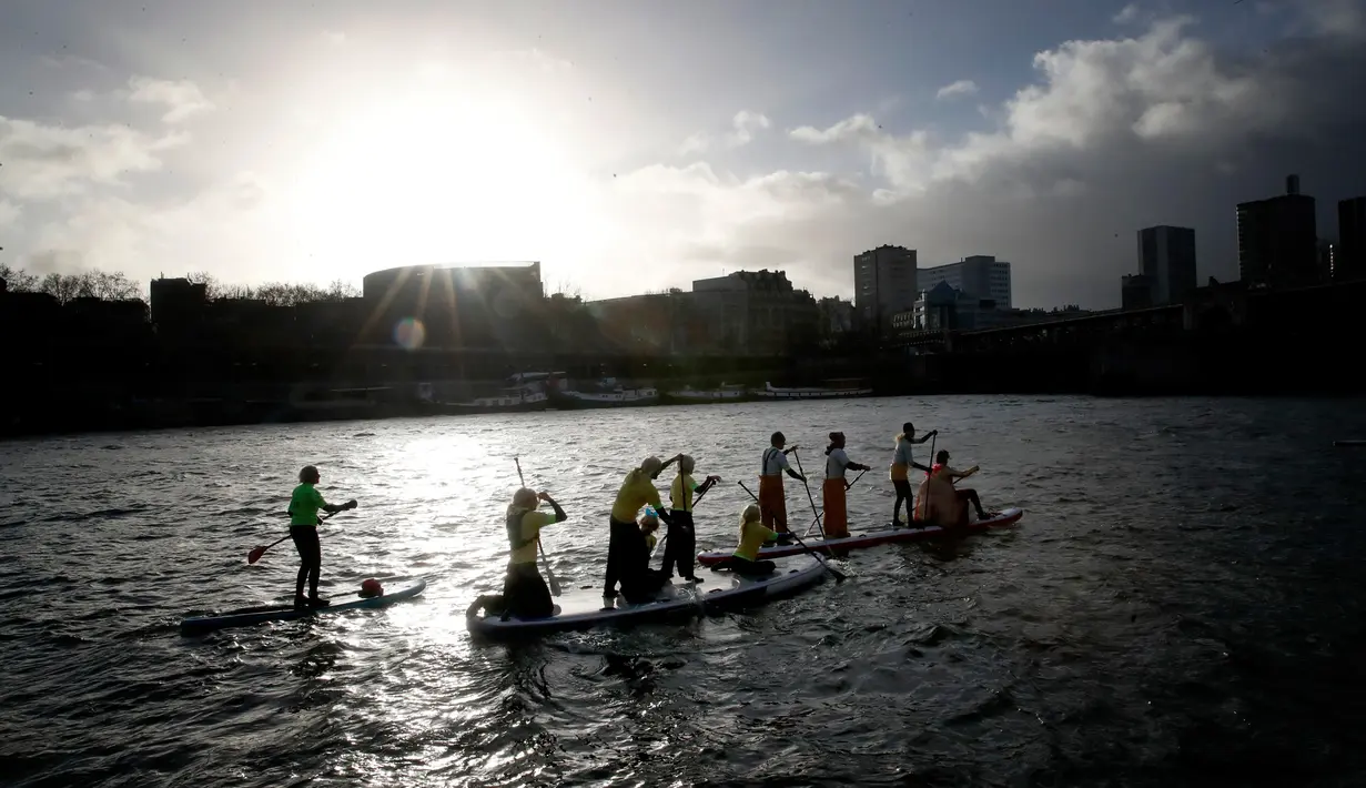 Peserta mengambil bagian dalam Nautic Paddle Race menyeberangi sungai Seine di Paris, Minggu (9/12). Sekitar 800 orang mengikuti lomba dayung sambil berdiri terbesar di dunia sejauh 11 km menyeberangi sungai Seine. (AP /Christophe Ena)