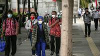 Para pekerja yang mengenakan masker berjalan kaki setelah meninggalkan perkantorannya di Jakarta, Rabu (2/2/2022). Satgas Penanganan COVID-19 turut mencatat sebanyak 25 orang meninggal dunia, membuat total angka kematian mencapai 144.373 orang. (Liputan6.com/Faizal Fanani)