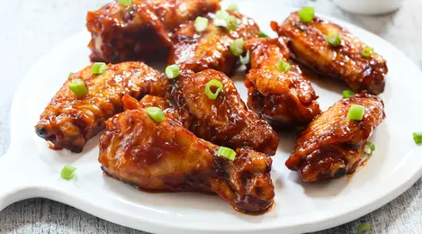 Sayap ayam madu panggang dengan warna keemasan dan kilauan madu, siap disajikan untuk acara spesial