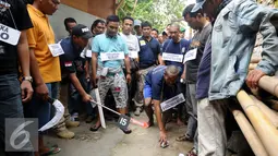 Salah satu tersangka melakukan reka ulang kejadian di kawasan Berlan, Jakarta, Jumat (19/2/2016). Tersangka memeragakan 54 adegan penyerangan terhadap dua anggota polisi hingga tewas. (Liputan6.com/Helmi Fithriansyah)