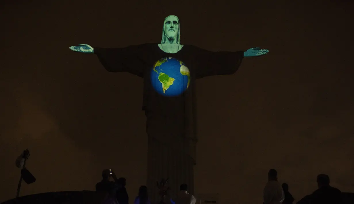 Patung Christ the Redeemer bermandi cahaya gambar bumi di Rio de Janeiro, Brasil, Rabu (18/3/2020). Pertunjukan ini untuk menunjukkan dukungan bagi mereka yang menderita virus corona COVID-19. (AP Photo/Silvia Izquierdo)