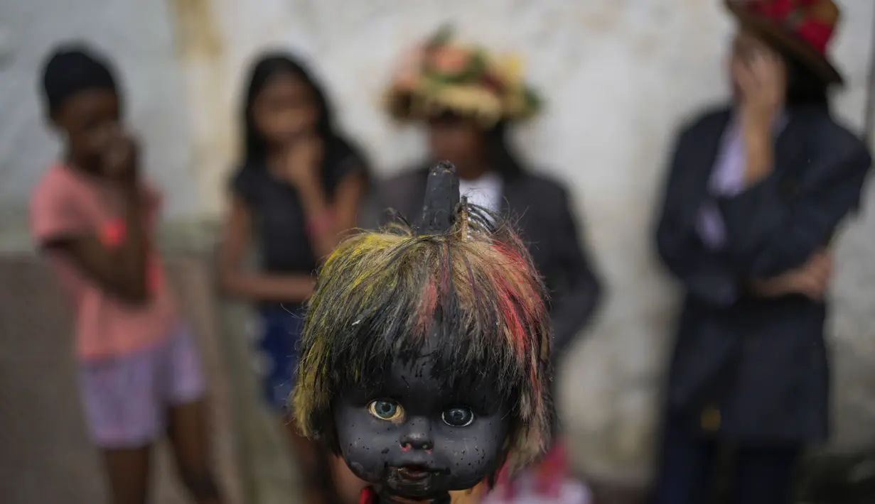 Orang yang bersuka ria berparade dengan kepala boneka yang ditusuk di atas tongkat selama perayaan Hari Tak Bersalah di Caucagua, Venezuela, Selasa (28/12/2021). Warga merayakan variasi hari raya itu dengan mengenakan pakaian tua, mengecat wajah mereka hitam dan lidah merah. (AP Photo/Matias Delacro
