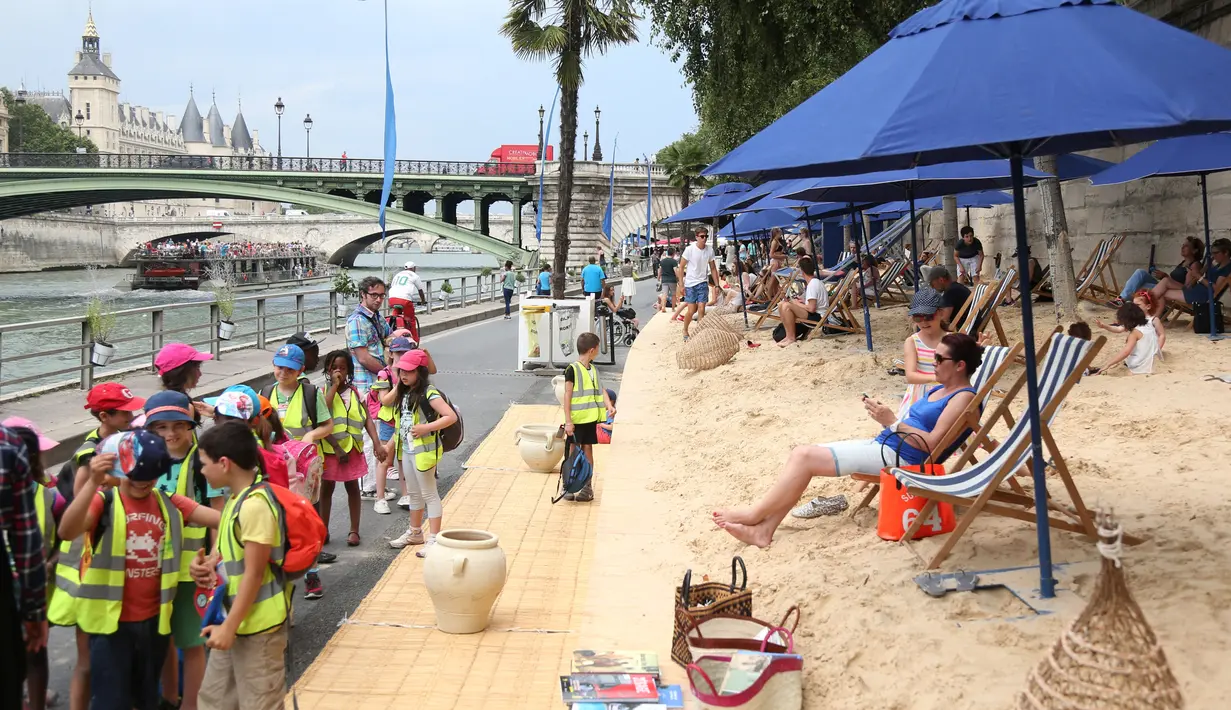 Warga bersantai dan berjemur di tepi sungai Seine pada hari pembukaan festival pantai Paris Plages, Paris, Prancis, (20/7). Meski baru-baru ini Prancis diserang banyak teror, warga tetap menyelenggarakan festival ini. (REUTERS / Charles Platiau)