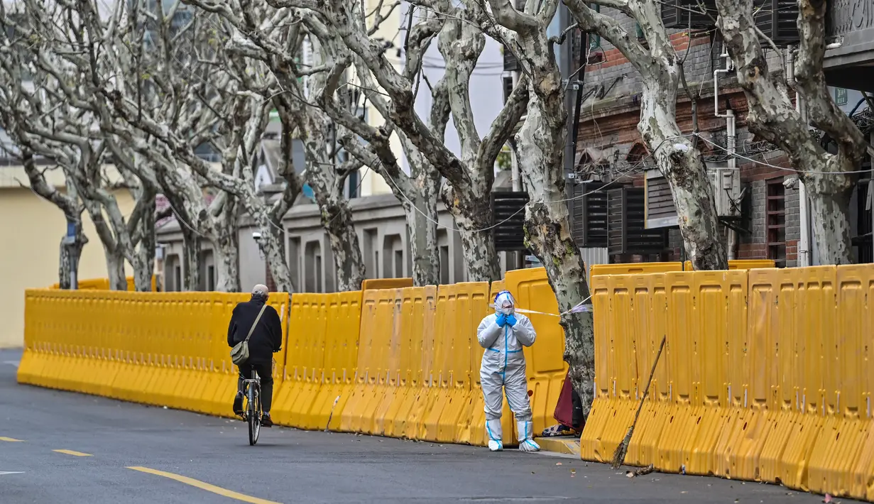 Seorang pekerja yang mengenakan alat pelindung diri berdiri di samping penghalang saat lockdown sebagai tindakan melawan virus corona COVID-19 di Distrik Jing'an, Shanghai, China, 31 Maret 2022. (Hector RETAMAL/AFP)