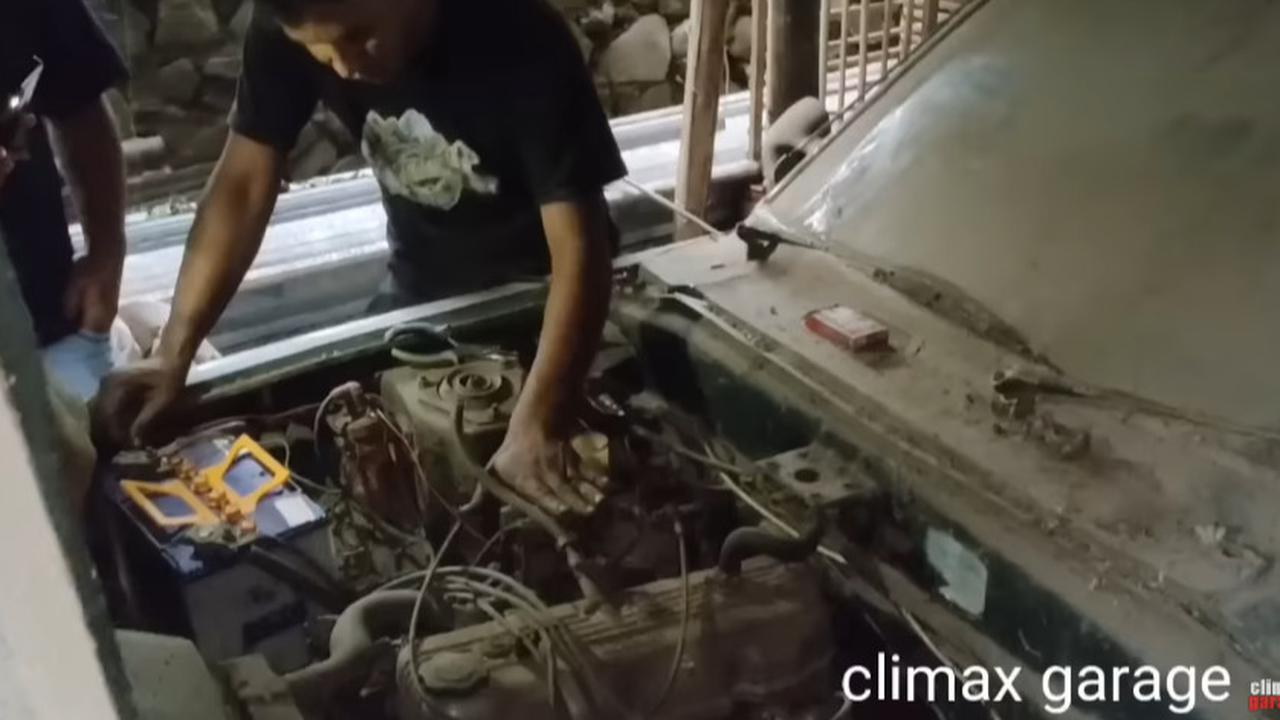 Seorang pria teknisi mesin mencoba memeriksa kondisi mesin dari mobil Mazda 808 tersebut. <br>