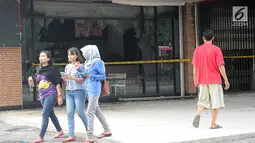Sejumlah orang melintas di depan gedung pusat perbelajaan Ramayana, Pasar Minggu, Jakarta, yang terbakar, Kamis (18/5). Tidak ada korban jiwa dalam insiden yang diduga karena korsleting ini. (Liputan6.com/Yoppy Renato)