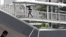 Warga menggunakan payung di Jembatan Penyebrangan Orang, kawasan Kuningan, Jakarta, Kamis (18/12/2021). BMKG memprakirakan potensi hujan lebat yang mungkin disertai petir dan angin kencang hingga 21 Februari di beberapa provinsi di Indonesia, termasuk DKI Jakarta. (Liputan6.com/Helmi Fithriansyah)