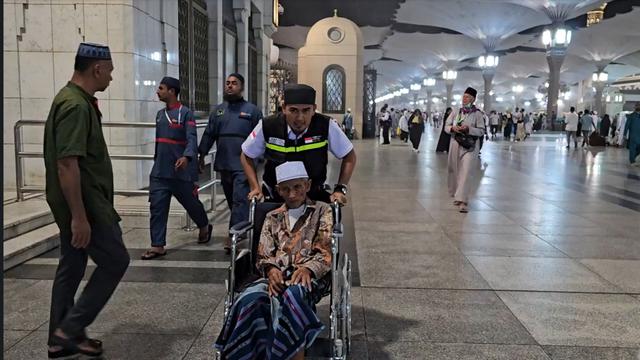 Petugas haji mengantar pulang jemaah haji lansia dari Masjid Nabawi menuju hotel menggunakan kursi roda.  (FOTO: MCH PPIH ARAB SAUDI 2023)