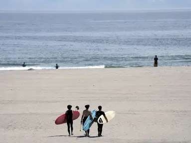 Orang-orang berjalan di pantai untuk berselancar di pantai Yotsukura, sekitar 30 kilometer (sekitar 18 mil) selatan pembangkit listrik tenaga nuklir Fukushima Daiichi, yang rusak akibat gempa bumi dan tsunami besar 11 Maret 2011, di Iwaki, timur laut Jepang, Sabtu, 26 Agustus 2023. (AP Photo/Eugene Hoshiko)