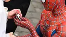 Seorang pria yang mengenakan kostum Spider-Man menyerahkan maskernya kepada Paus Fransiskus saat mereka bertemu di akhir audiensi umum mingguan di San Damaso Courtyard, Vatikan, Rabu (23/6/2021). Pria itu adalah Mattia Villardita (27) yang menghibur anak-anak di rumah sakit. (Alberto PIZZOLI / AFP)