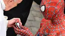 Seorang pria yang mengenakan kostum Spider-Man menyerahkan maskernya kepada Paus Fransiskus saat mereka bertemu di akhir audiensi umum mingguan di San Damaso Courtyard, Vatikan, Rabu (23/6/2021). Pria itu adalah Mattia Villardita (27) yang menghibur anak-anak di rumah sakit. (Alberto PIZZOLI / AFP)