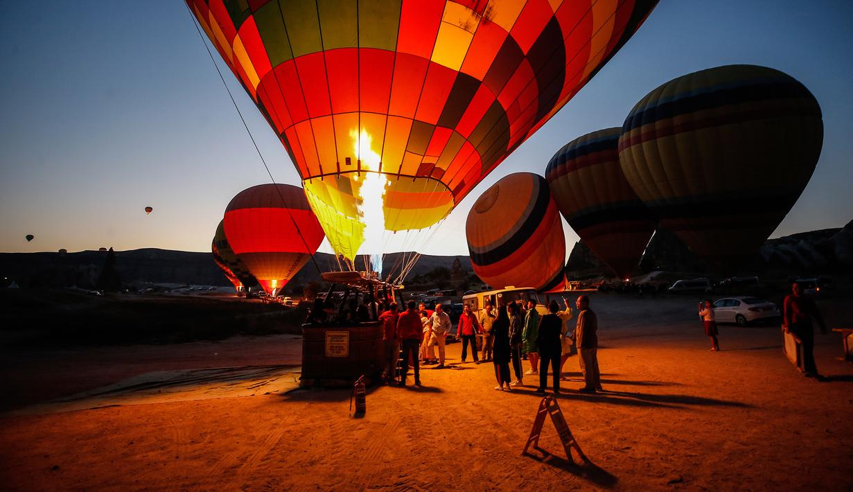 Wisatawan berkumpul saat balon udara disiapkan untuk menikmati pemandangan Kapadokia, Turki, Selasa (7/8). Cerobong Peri Kapadokia adalah lansekap batu vulkanik berbentuk kerucut yang menjulang tinggi ke langit. (AP Photo/Emrah Gurel)