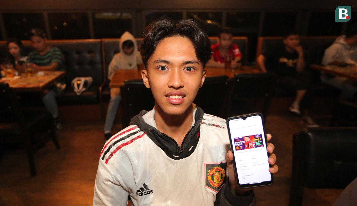 <p>Seorang penonton menunjukkan tanda pendaftaran melalui aplikasi Youniverse saar acara Roaring Night antara MU melawan West Ham yang berlangsung di Fomo Bar, Melawai, Jakarta, Minggu (04/02/2024) malam WIB. (Bola.com/Bagaskara Lazuardi)</p>