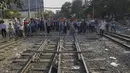 Demonstran berdiri di rel kereta api dalam upaya mengganggu layanan kereta selama protes terhadap kudeta militer di Mandalay, Myanmar (17/2/2021). Mereka berbondong-bondong memenuhi jalur kereta api di tengah terik matahari sambil mengangkat spanduk untuk mendukung gerakan pembangkangan. (AP Photo)