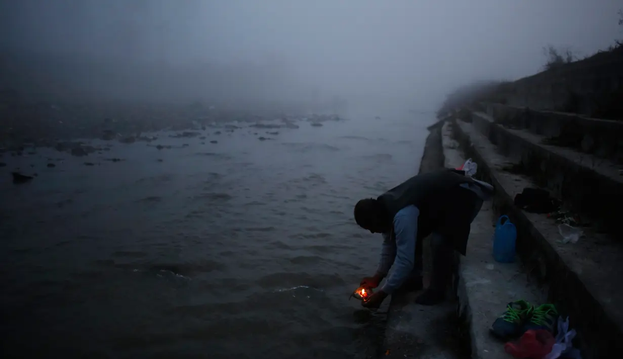 Seorang pria menghayutkan lilin di sungai Bagmati saat ritual Gaya Aunsi di Kathmandu, Nepal (21/12). Mereka percaya, dengan menggelar ritual ini dapat membantu keluarga mereka yang telah meninggal untuk menuju surga (AP Photo/Niranjan Shrestha)