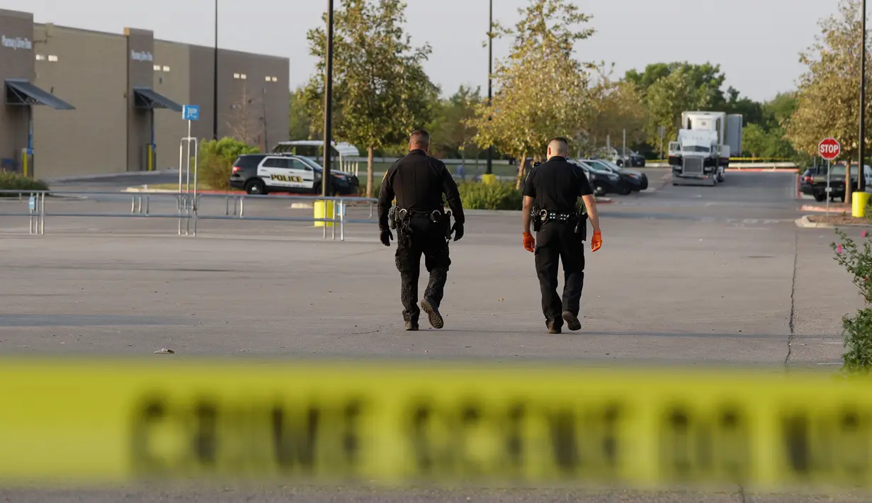 Petugas polisi berjalan mendekati truk yang berisi sembilan mayat di lapangan parkir sebuah supermarket, Texas, Minggu (23/7). Mayat-mayat itu ditemukan setelah Polisi mendapat telepon dari karyawan supermarket yang mencurigai truk itu (AP Photo/Eric Gay)