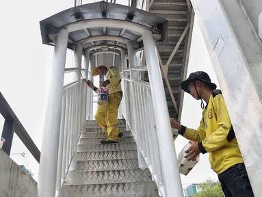 Petugas dari dinas terkait melakukan pengecatan di Jembatan Penyeberangan Orang (JPO) yang sudah diperbaiki di kawasan Daan Mogot, Jakarta Barat, Rabu (16/4/2025). (Liputan6.com/Angga Yuniar)