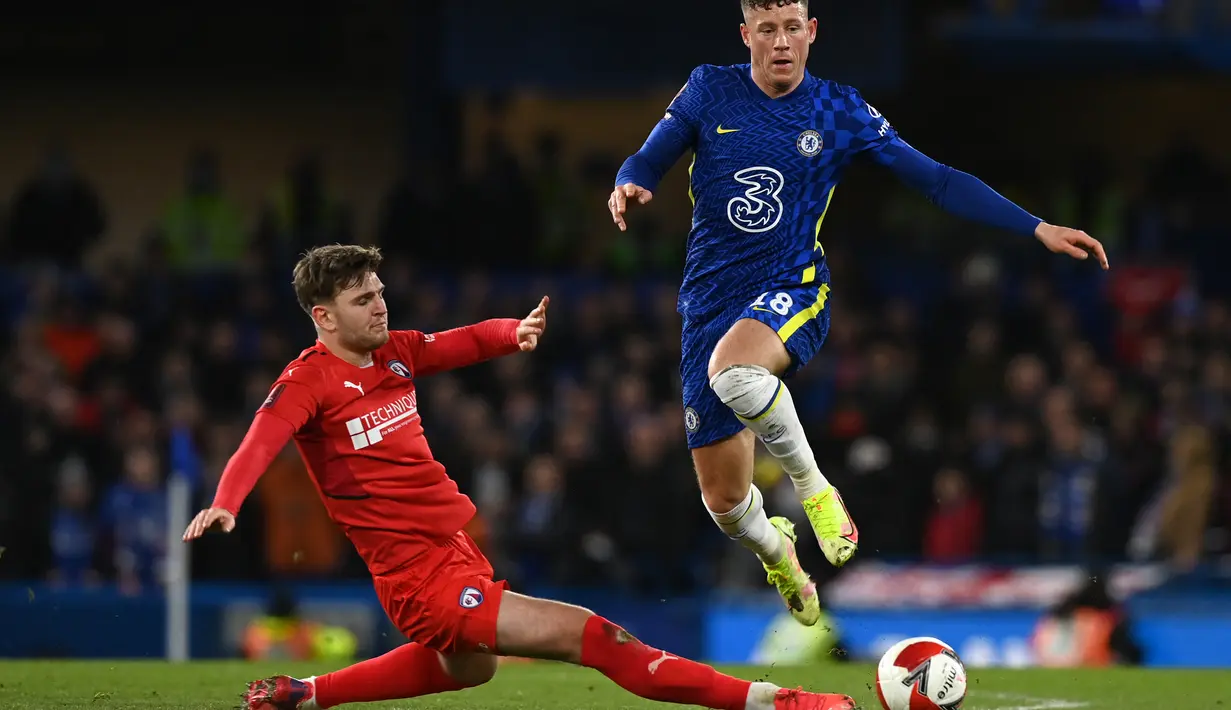 Bek Chesterfield Laurence Maguire meluncur untuk menantang gelandang Chelsea Ross Barkley pada putaran ketiga Piala FA di Stamford Bridge, Minggu (9/1/2022) dini hari WIB. Chelsea melenggang mulus melewat tim divisi kelima Chesterfield dengan kemenangan telak 5-1. (Glyn KIRK / AFP)