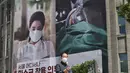 Seorang pria berjalan melewati spanduk yang menganjurkan wajib mengenakan topeng di depan Balai Kota Seoul di Seoul (4/9/2020). Korea Selatan melaporkan 198 kasus Covid-19 baru pada 4 September, hari ke-22 berturut-turut meningkat tiga digit. (AFP/Jung Yeon-je)