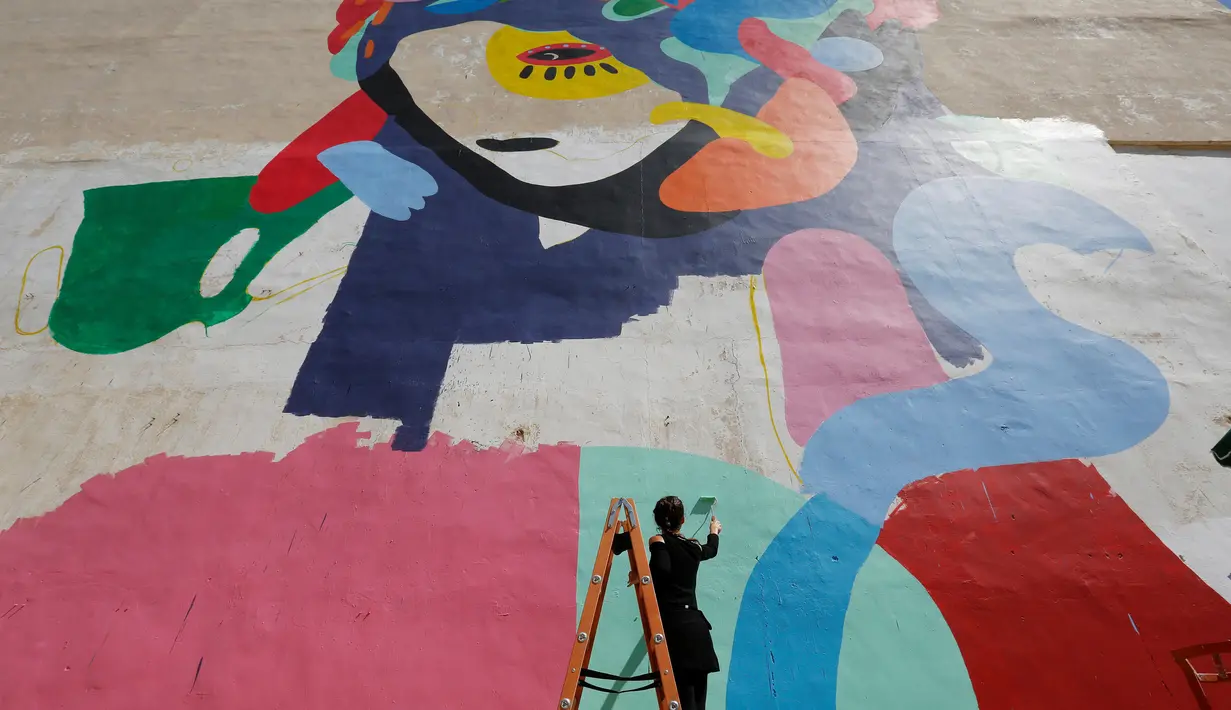 Tarsila Schubert menggunakan tangga membuat karya mural di dinding Museum Seni Terbuka, Kota Amman, Yordania, Kamis (29/9). Mural karya Tarsila Schubert asal Brasil itu menghiasi Museum Seni Terbuka, Kota Amman, Yordania. (REUTERS/Muhammad Hamed)