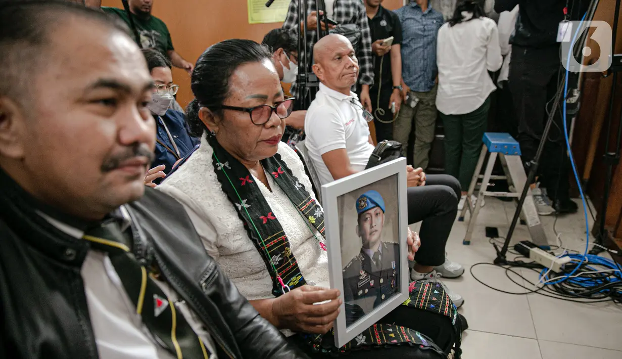 Ibunda Nofriansyah Yosua Hutabarat atau Brigadir J, Rosti Simanjuntak (tengah) membawa foto sang anak saat menghadiri sidang vonis terdakwa Ferdy Sambo di Pengadilan Negeri Jakarta Selatan, Senin (13/2/2023). Rosti didampingi kuasa hukum keluarga Martin Lukas Simanjuntak menonton langsung sidang putusan terhadap Ferdy Sambo. (Liputan6.com/Faizal Fanani)