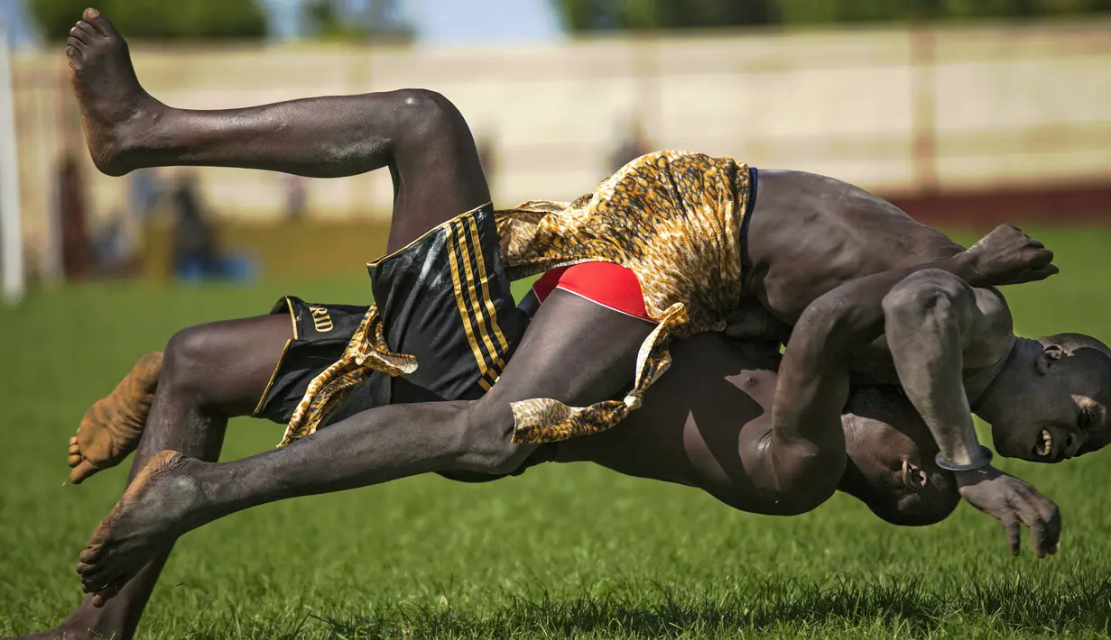 Pegulat saling menjatuhkan dalam Kompetisi Gulat Nasional Sudan Selatan di Stadion Juba, Sudan (20/4).Turnamen besar ini pernah dihentikan saat perang saudara terjadi pada bulan Desember tahun 2013. (CARL DE SOUZA / AFP)