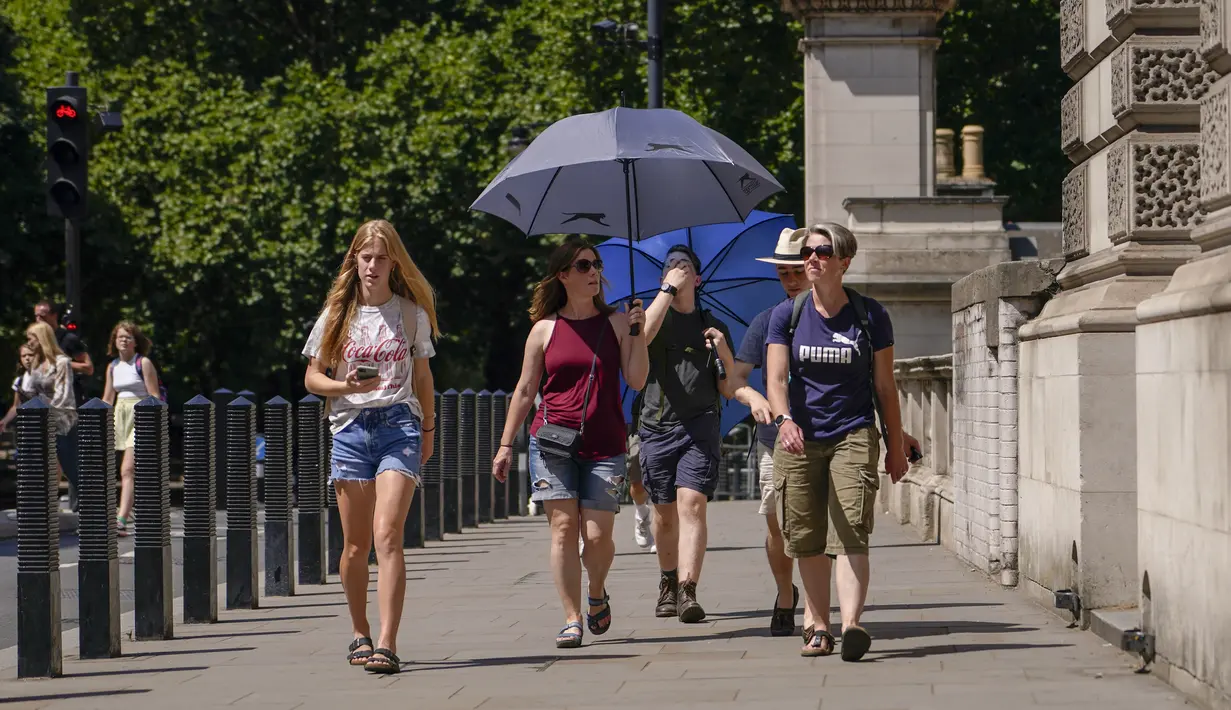 <p>Turis memegang payung untuk berlindung dari matahari, di London, Senin (18/7/2022). Pemerintah Inggris telah mengeluarkan peringatan suhu panas ekstrem pertama di negara itu, sementara cuaca panas dan kering yang telah melanda daratan Eropa selama seminggu terakhir bergerak ke utara, mengacaukan perjalanan, layanan kesehatan, dan sekolah. (AP Photo/Alberto Pezzali)</p>