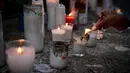 Seorang wanita menyalakan lilin untuk memberikan penghormatan kepada para korban tewas di depan klub malam Jet Set di Santo Domingo, Dominika pada 11 April 2025. (MARTIN BERNETTI/AFP)