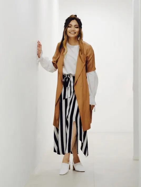 Paduan motif garis-garus untuk rok dan atasan putih sangat pas dipakai oleh presenter kondang yang satu ini. Selain itu, Rina juga memadukannya dengan outer berwarna coklat. Unik banget ya? (Instagram/rinanose16)