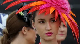 Seorang wanita memakai hiasan kepala menyerupai bunga saat menghadiri balap kuda Melbourne di arena pacuan kuda Flemington Racecourse di Melbourne, Australia (1/11).  Mereka tampil gaya saat menyaksikan kompetisi balap kuda ini. (AFP/Paul Crock)