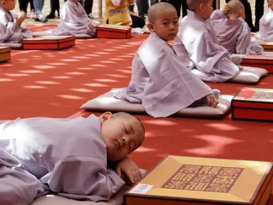 Seorang anak lelaki bernama Buddha Myung Bub tidur siang setelah kepalanya dicukur saat kebaktian merayakan ulang tahun ke-2.563 Buddha pada 12 Mei, di Kuil Jogye di Seoul, Korea Selatan, Senin (22/4). Sepuluh anak terpilih menjadi peserta peringatan ini. (AP Photo/Ahn Young-joon)