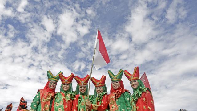 <span>Penari dengan pakaian tradisional mengibarkan bendera Merah-Putih usai beraksi pada penutupan Tour de Singkarak 2016 di Kota Padang, Sumatera Barat, (14/8/2016). (Bola.com/Nicklas Hanoatubun)</span>