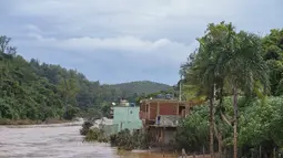 Banjir menutupi jalan perumahan di Raposos, negara bagian Minas Gerais, Brasil, Selasa (11/1/2022). Tanah longsor akibat hujan deras telah menewaskan sedikitnya 12 orang dan pihak berwenang sedang memantau bendungan yang bisa jebol. (AP Photo/Eugenio Savio)