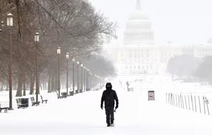 Seorang pria berjalan di kawasan National Mall saat salju turun di Washington, pada Minggu (25/1/2026). (Dok. AFP/Amid Farahi)