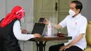 Presiden Joko Widodo atau Jokowi menjalani penapisan kesehatan saat mengikuti vaksinasi COVID-19 di Istana Merdeka, Jakarta, Rabu (13/1/2021). Usai penapisan kesehatan, Jokowi kemudian menuju meja berikutnya di mana proses penyuntikan dilakukan. (Biro Pers Sekretariat Presiden/Muchlis Jr)