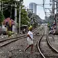 Seorang wanita melintasi rel kereta di kawasan pemukiman padat Pejompongan di tengah pandemi COVID-19, Jakarta, Kamis (28/1/2020). Sensus Penduduk 2020 (SP2020) mencatat penduduk DKI Jakarta pada bulan September 2020 sebanyak 10,56 juta  jiwa. (Liputan6.com/Johan Tallo)