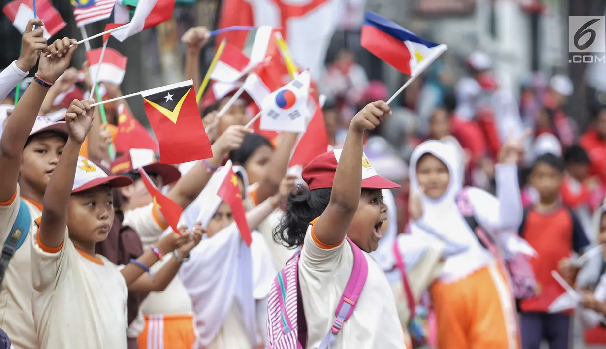 Siswa-siswi SD membawa bendera negara peserta Asian Games 2018 untuk menyambut Kirab Obor di kawasan Jati Padang, Pasar Minggu, Rabu (15/8). Mereka memenuhi jalanan untuk menyaksikan langsung Pawai Obor Asian Games 2018. (Liputan6.com/Faizal Fanani)