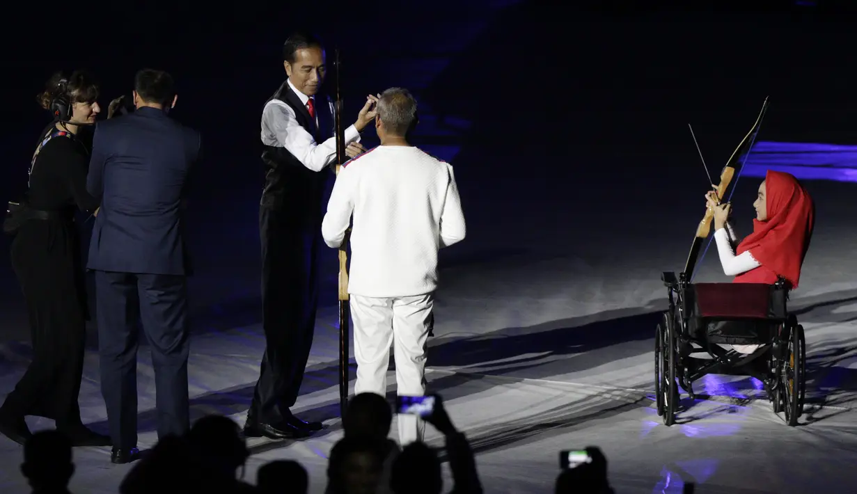 Presiden Indonesia, Joko Widodo, bersama penyandang disabilitas memanah tugu saat pembukaan Asian Para Games di SUGBK, Jakarta, Sabtu (06/10/2018). Acara tersebut dimeriahkan dengan aksi para penyandang disabilitas. (Bola.com/M Iqbal Ichsan)
