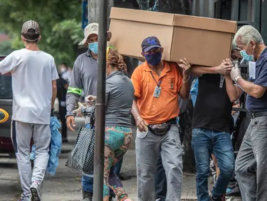 Pekerja makam membawa jenazah dalam peti mati kardus untuk dimakamkan di Pemakaman Umum di Guayaquil, Ekuador, Senin (6/4/2020). Kehabisan peti mati, kota terbesar di Ekuador yang menjadi klaster wabah virus corona itu terpaksa menggunakan kotak kardus untuk korban Covid-19. (AP/Luis Perez)