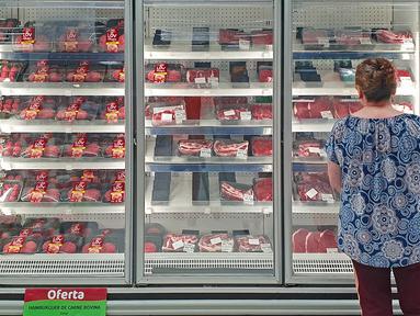 Seorang pelanggan memeriksa bagian daging sapi sebuah supermarket di Curitiba, Brasil, Kamis (23/2/2023). Mulai 23 Februari, Brasil menangguhkan sementara ekspor daging sapinya ke China, pembeli utama mereka, mengikuti protokol kesehatan resmi setelah kasus bovine spongiform encephalopathy atau disebut juga Penyakit Sapi Gila, dikonfirmasi oleh Kementerian Pertanian. (Photo by Eduardo Matysiak / AFP)
