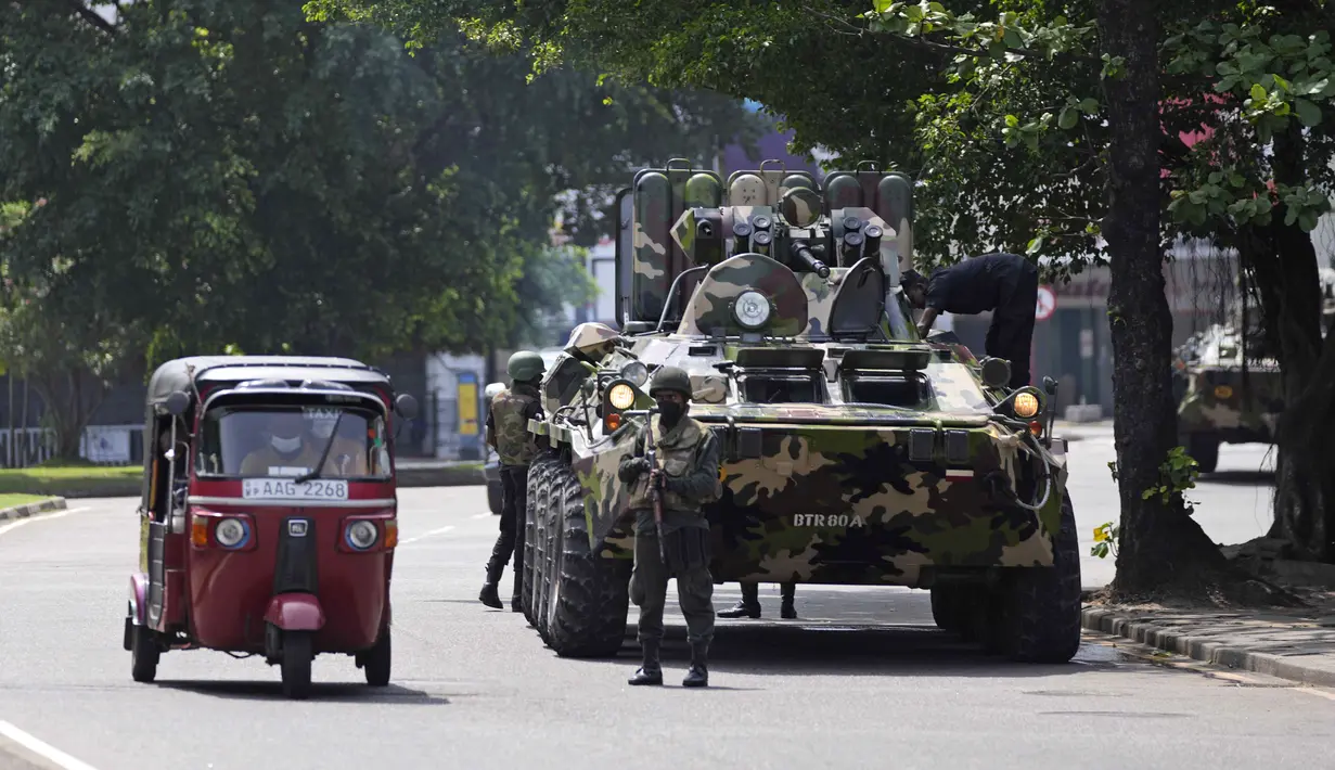 <p>Pengemudi bajaj melintas dekat tentara Sri Lanka yang berpatroli selama jam malam di Kolombo, Rabu, 11 Mei 2022. Kementerian pertahanan Sri Lanka pada Selasa memerintahkan pasukan keamanan untuk menembak siapa pun yang menyebabkan korban jiwa atau properti publik untuk mencegah pembakaran yang meluas dan kekerasan massa yang menargetkan pendukung pemerintah. (AP Photo/Eranga Jayawardena)</p>
