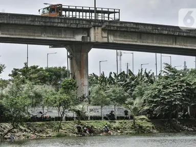 Truk melintas di atas lokasi pemancingan warga di waduk kawasan Sungai Bambu, Tanjung Priok, Jakarta, Minggu (17/1/2021). Waduk buatan di bawah Jalan Tol Pelabuhan tersebut menjadi wisata alternatif menghabiskan akhir pekan tanpa mengeluarkan biaya atau gratis. (merdeka.com/Iqbal S. Nugroho)