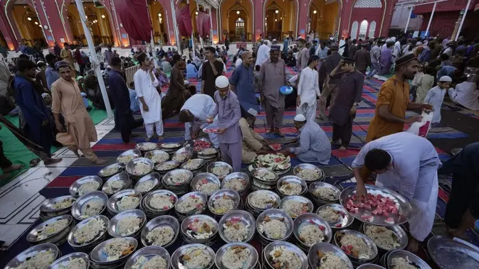 Volunteer membagikan piring makanan kepada orang-orang untuk berbuka puasa selama bulan suci Ramadhan, di masjid Memon di Karachi, Pakistan, Selasa, 12 Maret 2024. (AP Photo/Fareed Khan)