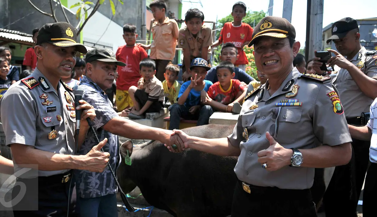 Inspektur Pengawas Daerah Kombes Polda Metro Jaya Didit Prabowo (kanan) bersama Kepala Polisi Resort Jakarta Pusat Hendro Pandowo (kiri) menyerahkan dua ekor sapi kurban di kawasan Johar Baru, Jakarta, Rabu (23/9/2015). (Liputan6.com/Gempur M Surya)