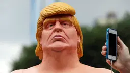 Warga memfoto kepala patung Donald Trump tanpa busana yang dipajang di Union Square Park, AS, Kamis (18/8). Patung Capres AS dari Partai Republik ini juga dipajang di San Francisco, Los Angeles, Cleveland, dan Seattle. (REUTERS/Brendan McDermid)