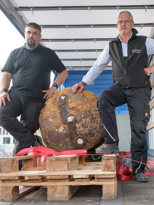 Pakar bom Rene Bennert dan Dieter Schweizler berpose di dekat bom Perang Dunia II di Frankfurt, Jerman, (3/9). Bom tersebut ditemukan di sebuah lokasi konstruksi yang dekat dengan kompleks Goethe University Frankfurt. (AFP Photo/Thomas Lohnes)